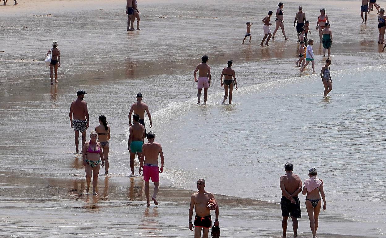 Paseantes por la playa de La Concha de Donostia, antes de la llegada de la galerna ayer. 