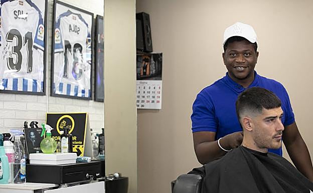 Bilal le corta el pelo al remero de Donostiarra, Igor Frances, en su barbería de Hernani. 
