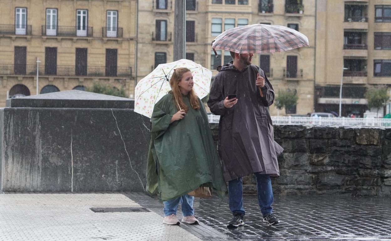 Una pareja se resguarda de la lluvia, ayer en San Sebastián. 