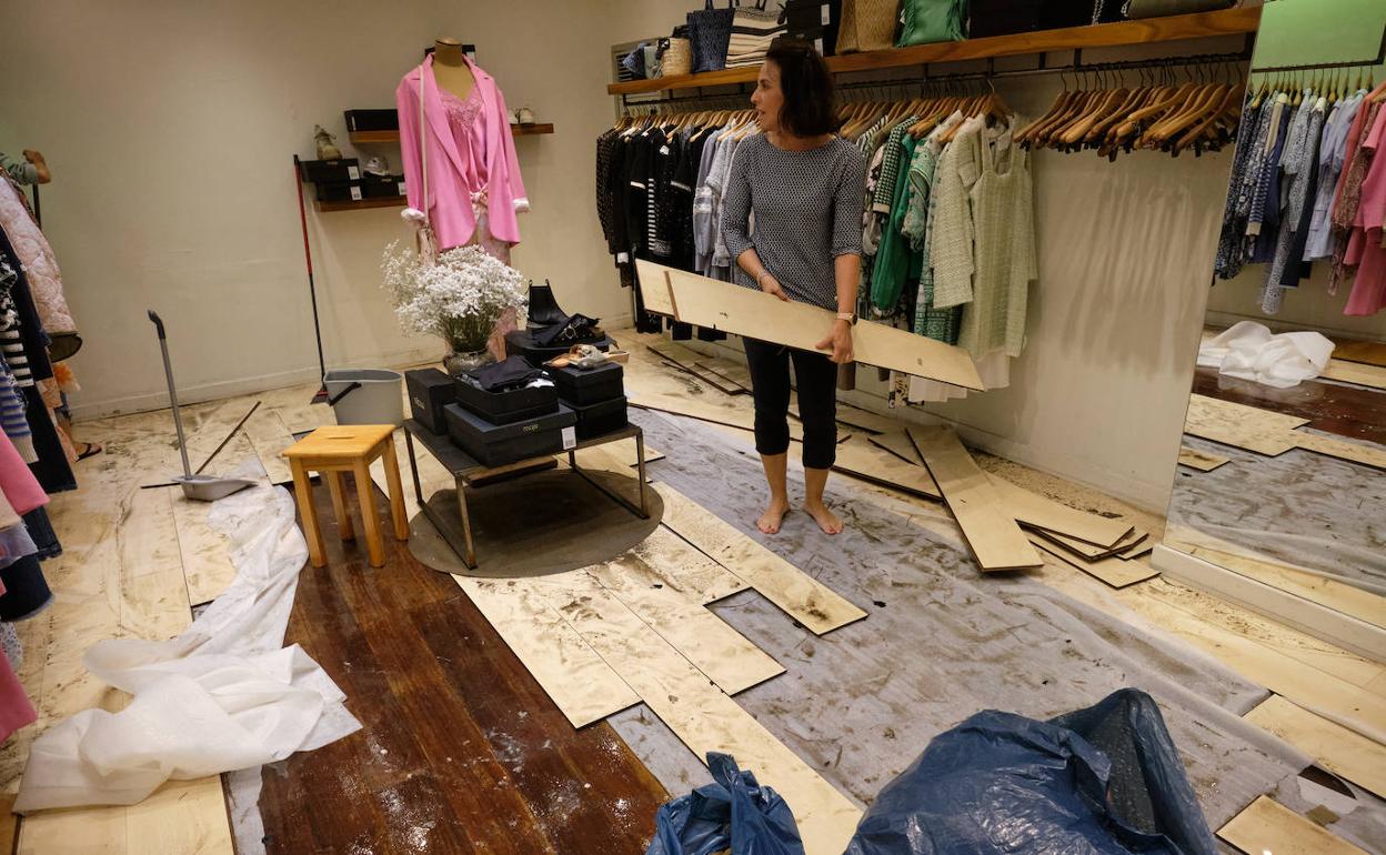 Regina, propietaria del comercio Maje, con las tablas de madera que el agua levantó en el suelo del establecimiento.