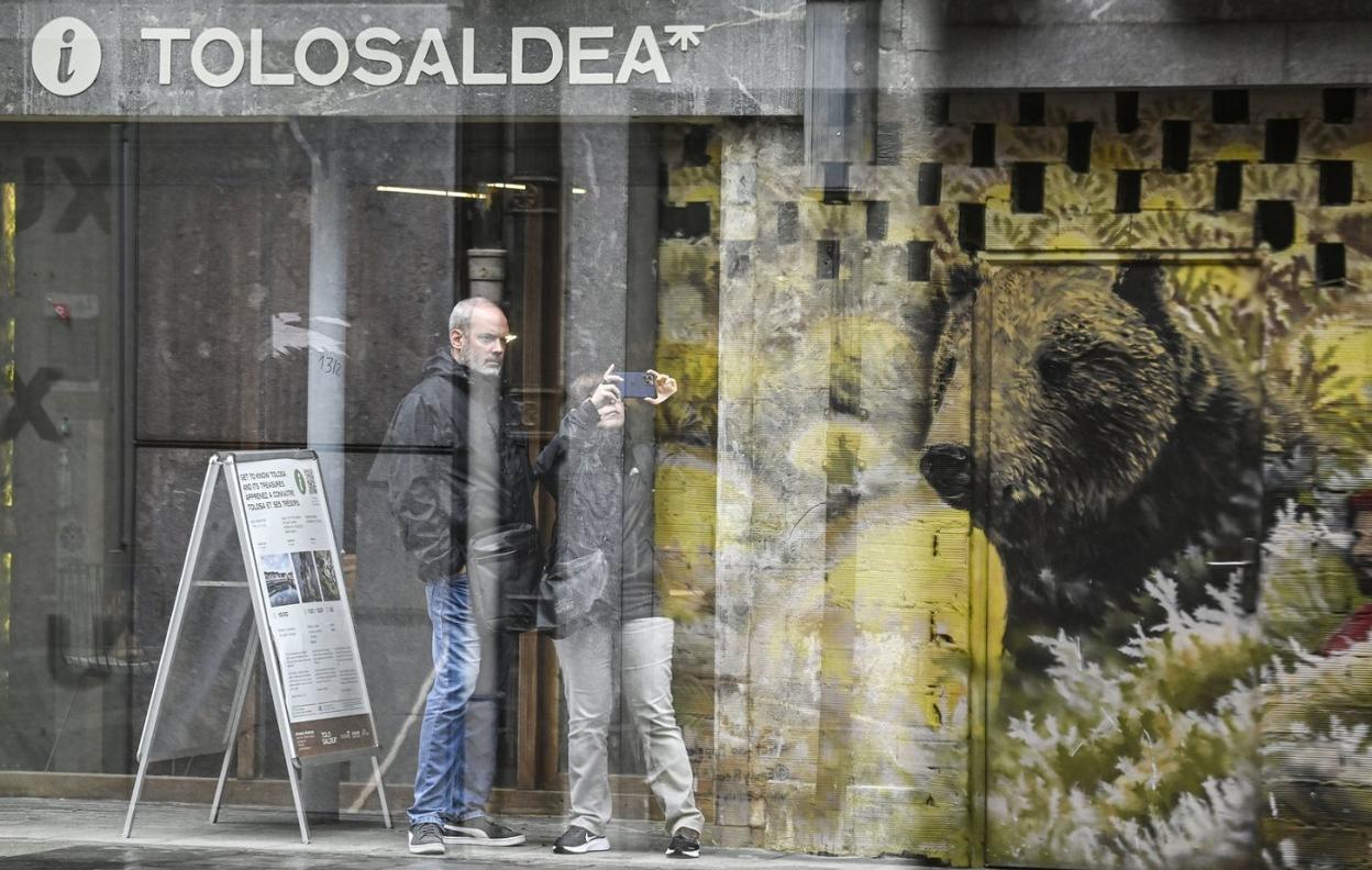 Dos visitantes fotografían el edificio del ayuntamiento en el exterior de la nueva oficina de turismo de Tolosaldea. 
