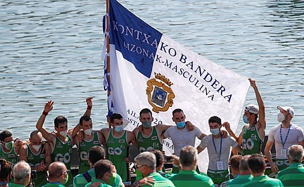 Los remeros de Hondarribia con la Bandera de La Concha 2020 en una rampa vacía de aficionados y con los remeros portando mascarilla. 