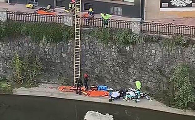 Sanitarios atienden al hombre que se lanzó al río Oria a su paso por el centro de Beasain.