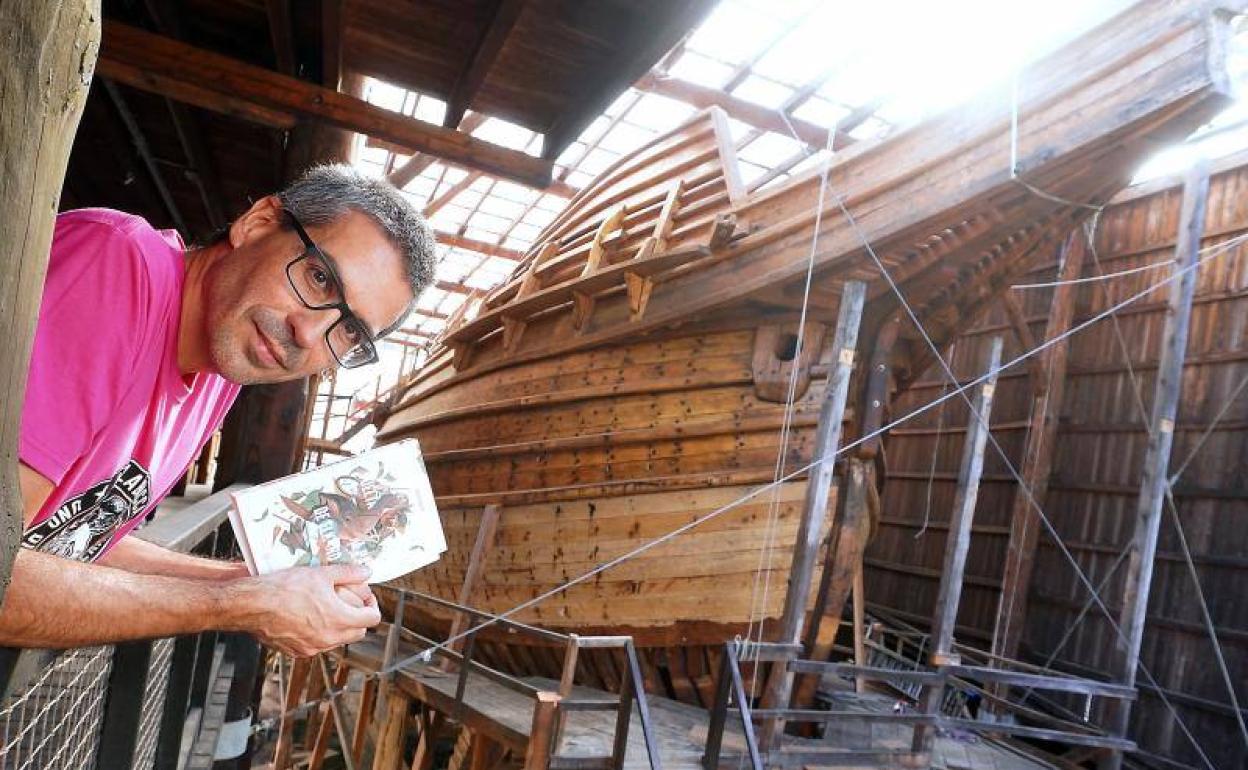 Ander Izagirre, con su libro, en la factoría marítima Albaola, junto a la réplica en construcción de la nao 'San Juan'. 
