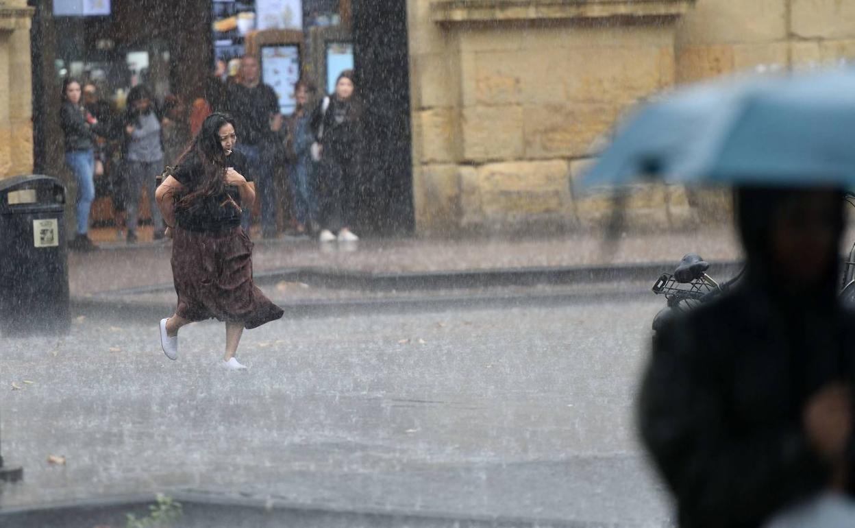 Una mujer corre para resguardarse en un clásico día de lluvia en Donostia. 