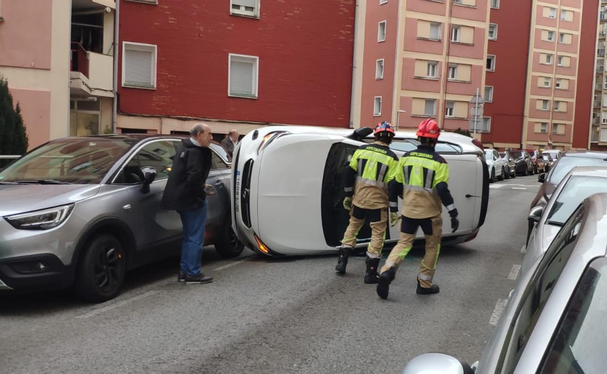 Los bomberos se acercan al vehículo volcado esta mañana en la calle Romualdo Galdós de Eibar. 