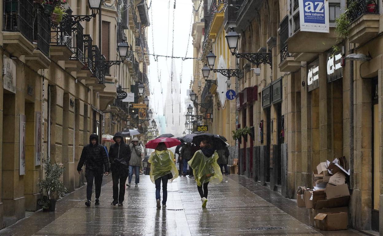 Varias personas pasean por la Parte Vieja de Donostia la lluviosa mañana de este lunes.
