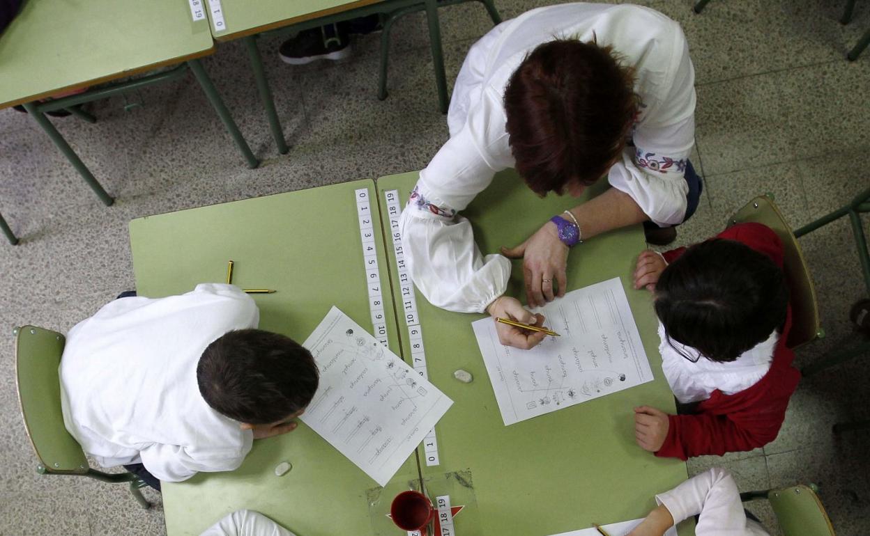 Dos alumnos atienden a las indicaciones de su profesora en clase. 