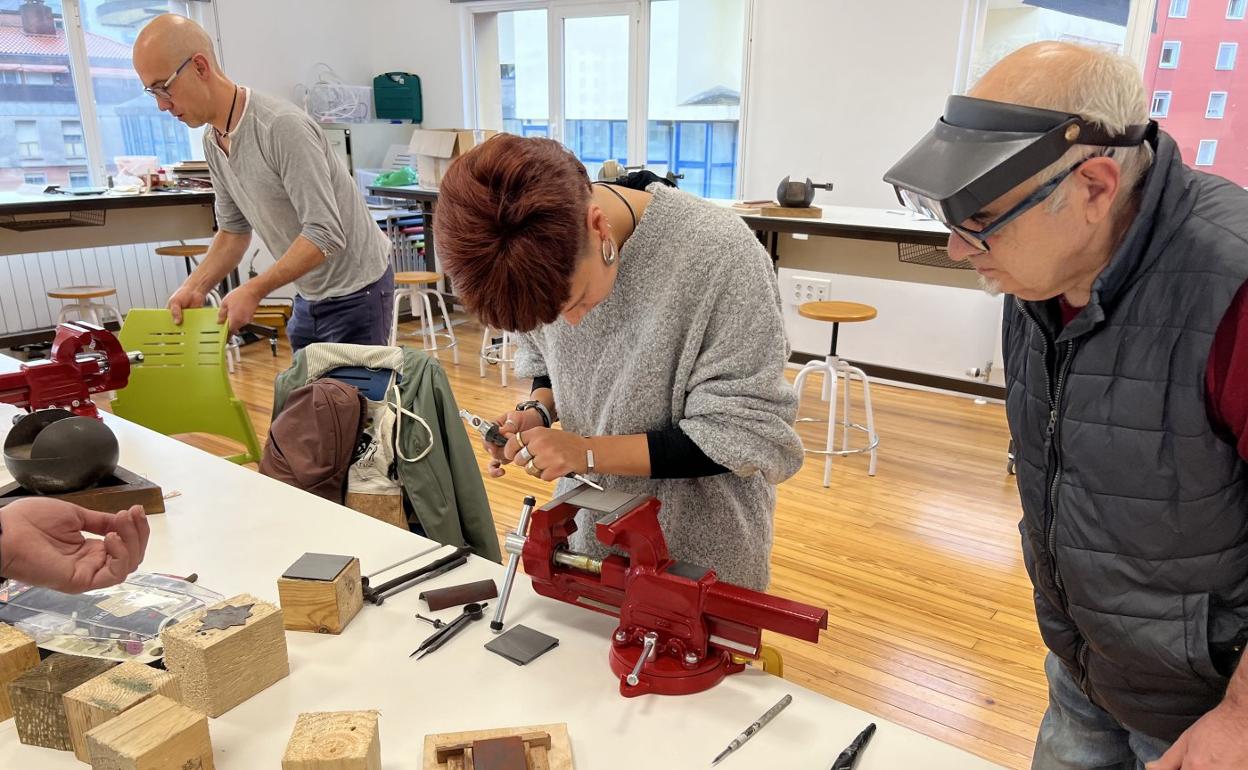 El profesor de grabado Armando Madinabeitia sigue el trabajo que realiza una alumna del taller en Armeria Eskola. 