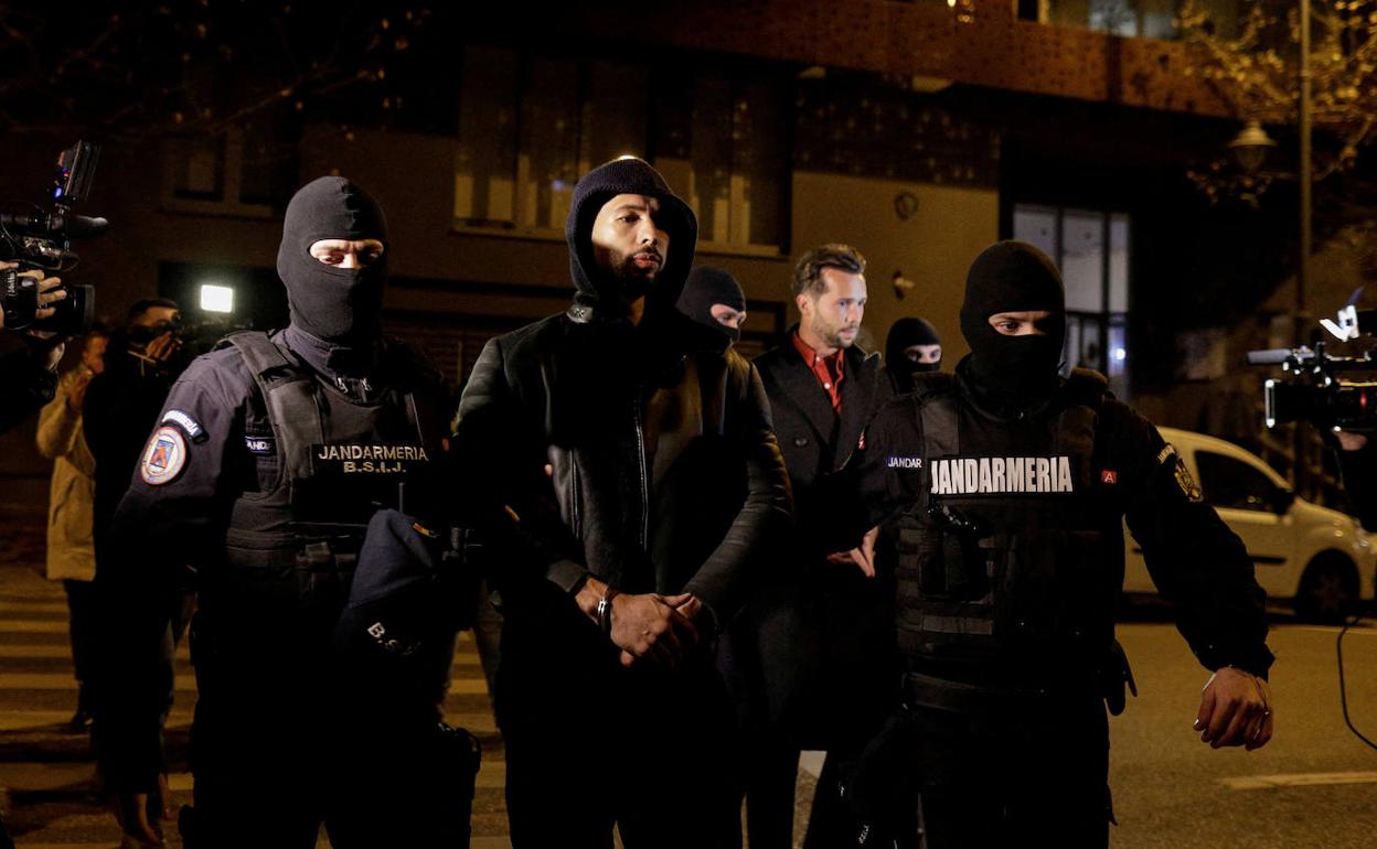 El influencer Andrew Tate sale esposado y acompañado por la policía rumana.