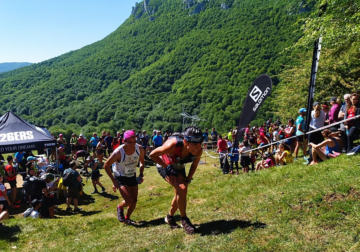 Dos de los participantes de la edición de 2022 corren entre la multitud de aficionados.