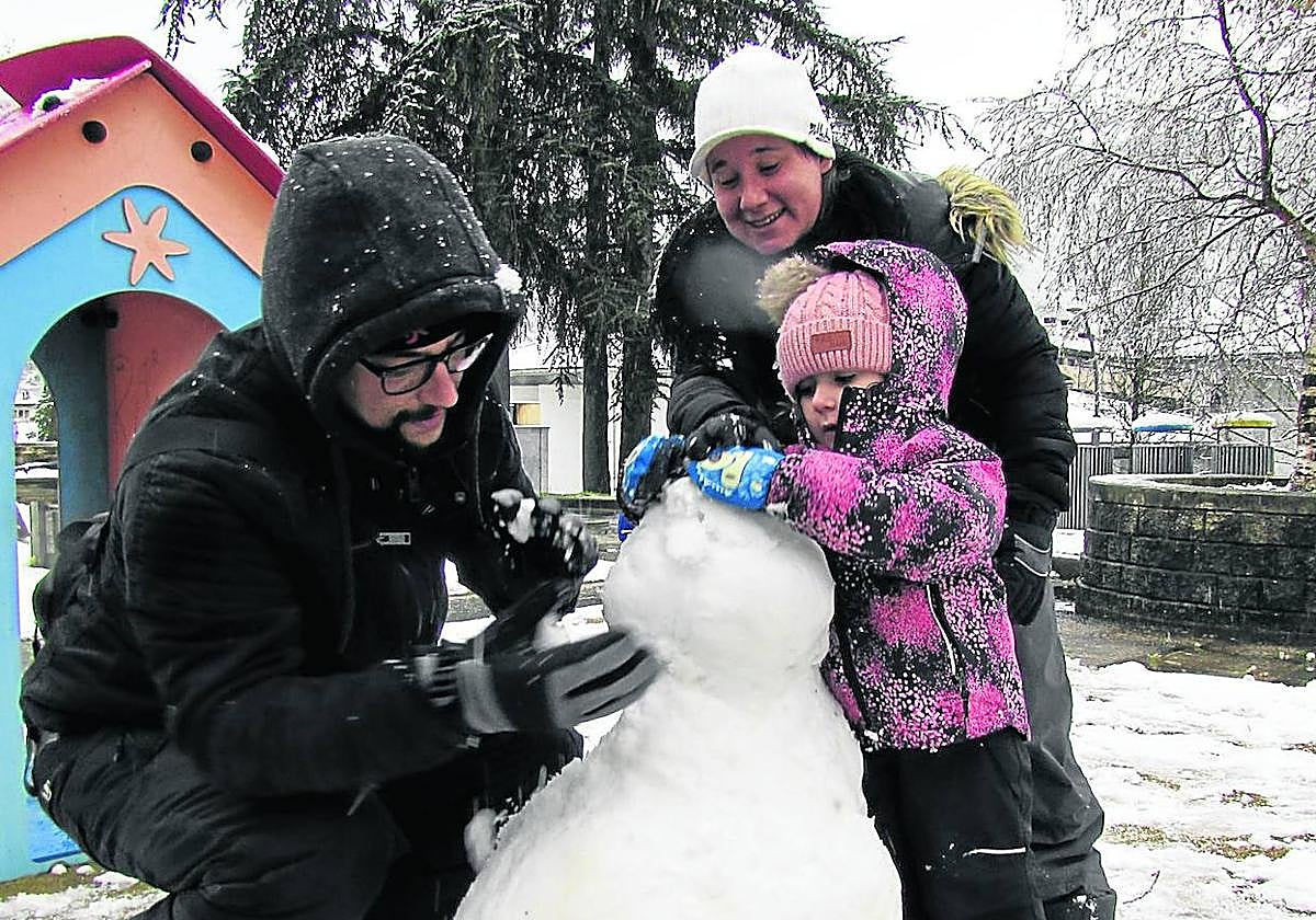 La pequeña Nora, de 4 años, haciendo un muñeco de nieve en Arrasate con ayuda de sus padres.
