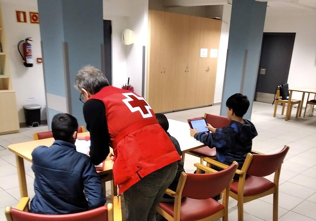 Un grupo de tres estudiantes atendidos por un voluntario en las dependencias del Hogar del Jubilado