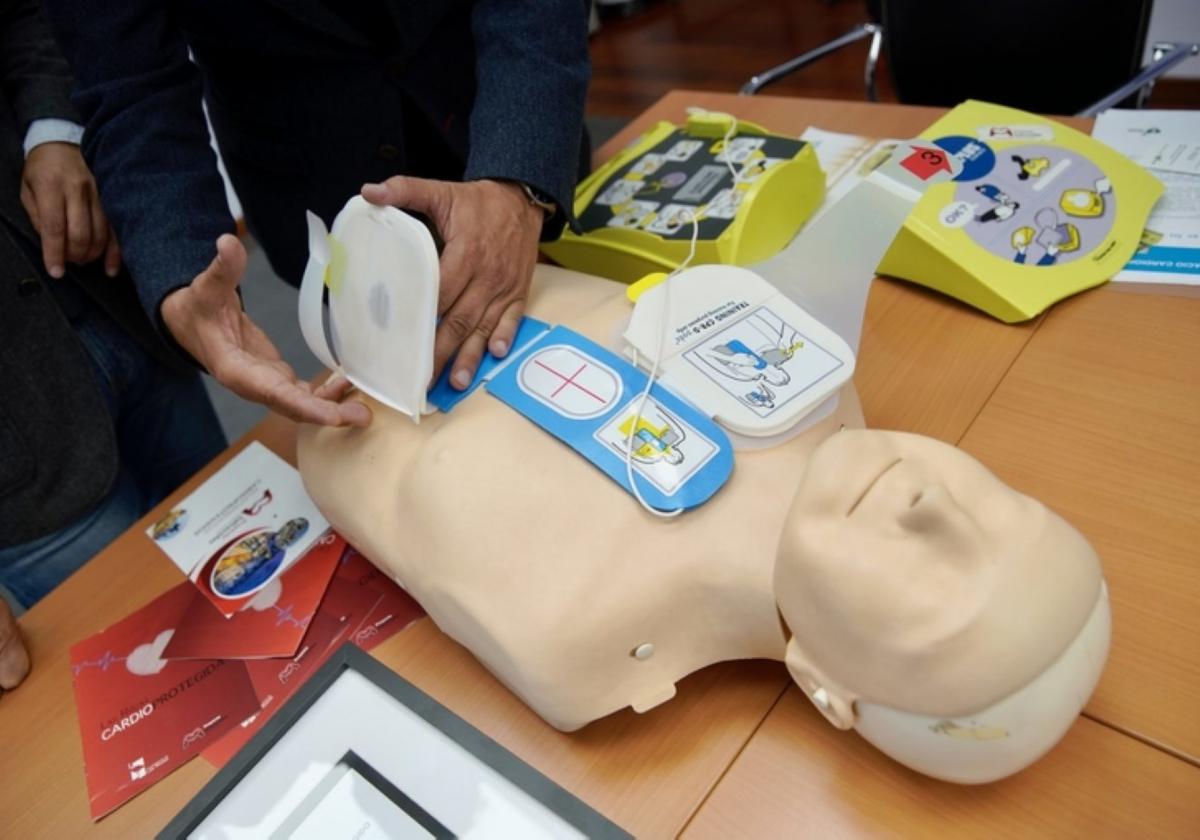 Un hombre enseña a utilizar un desfibrilador con un muñeco.