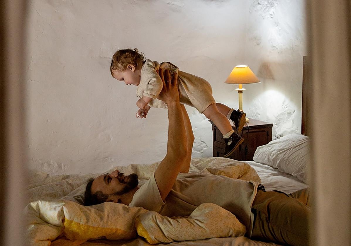 Un padre juega con su hijo en un dormitorio.
