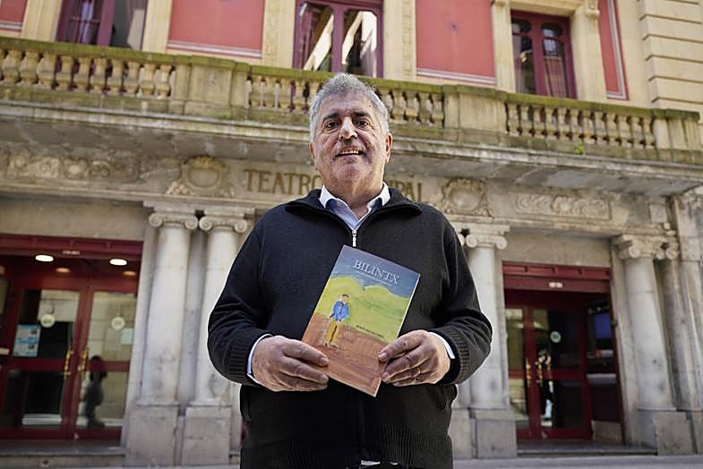 Jesús Eguiguren con su libro sobre Bilintx (el dibujo de la portada es suyo) ante el teatro Principal, donde trabajaba y vivía el bertsolari y donde cayó la bomba que acabaría con su vida unos meses después.