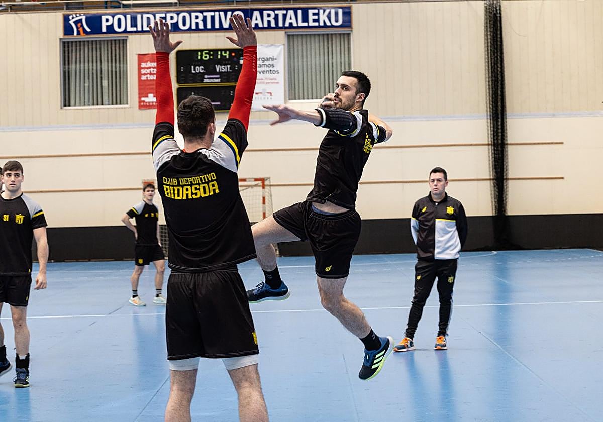 Jon Azkue lanzando a portería en un entrenamiento con la oposición de Eneko Furundarena.
