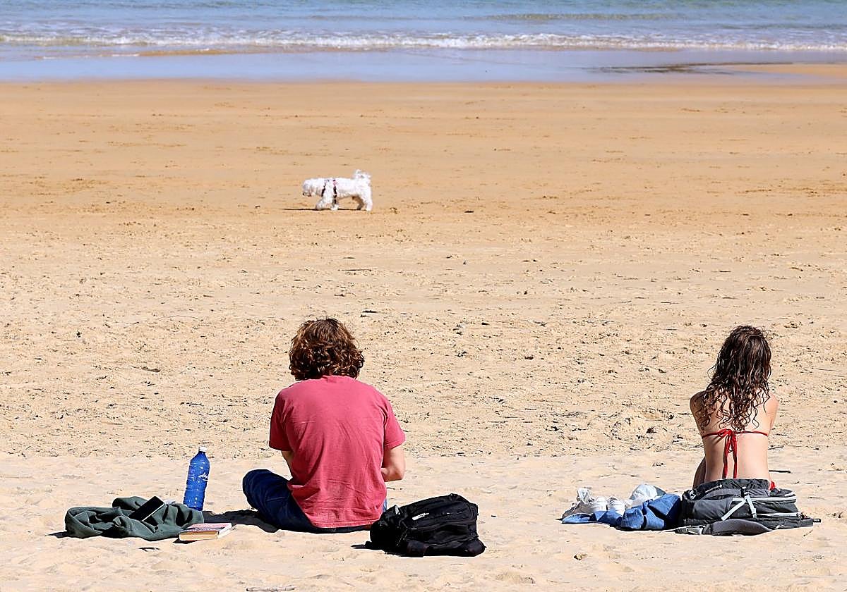 Dos personas disfrutan del buen tiempo y el calor en la playa de Ondarreta.