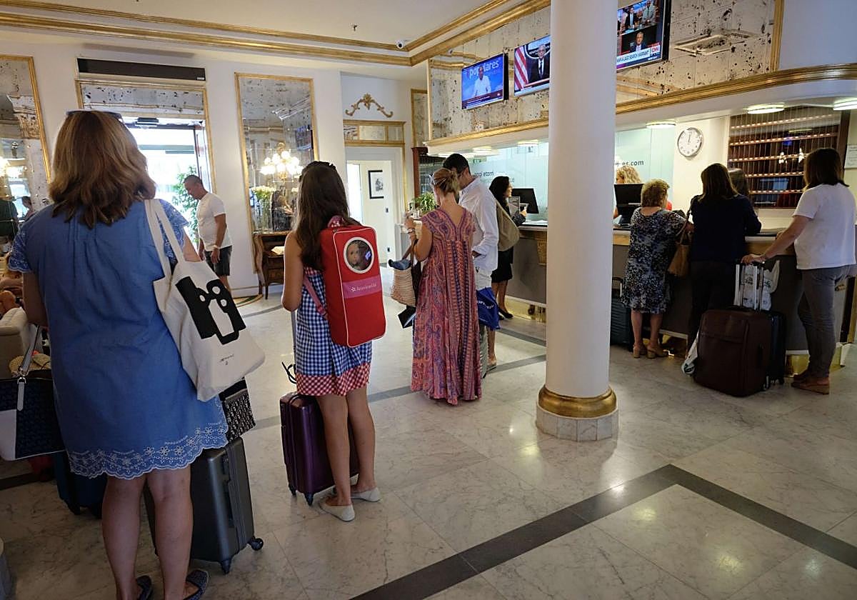 Varias turistas aguardan con sus maletas ante la recepción de un céntrico hotel donostiarra.