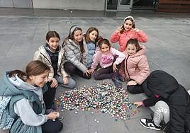Varios niños muestran su colección de chapas tras una tarde buscándolas por los bares.