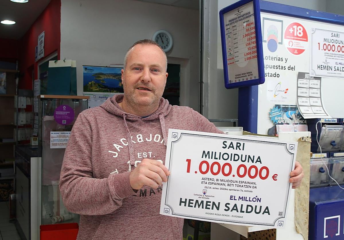 Gorka Iparragirre posa con el cartel que acredita la venta del boleto premiado con un millón de euros en su quiosco del centro comercial BM.
