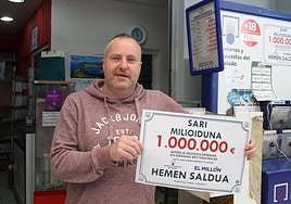 Gorka Iparragirre posa con el cartel que acredita la venta del boleto premiado con un millón de euros en su quiosco del centro comercial BM.