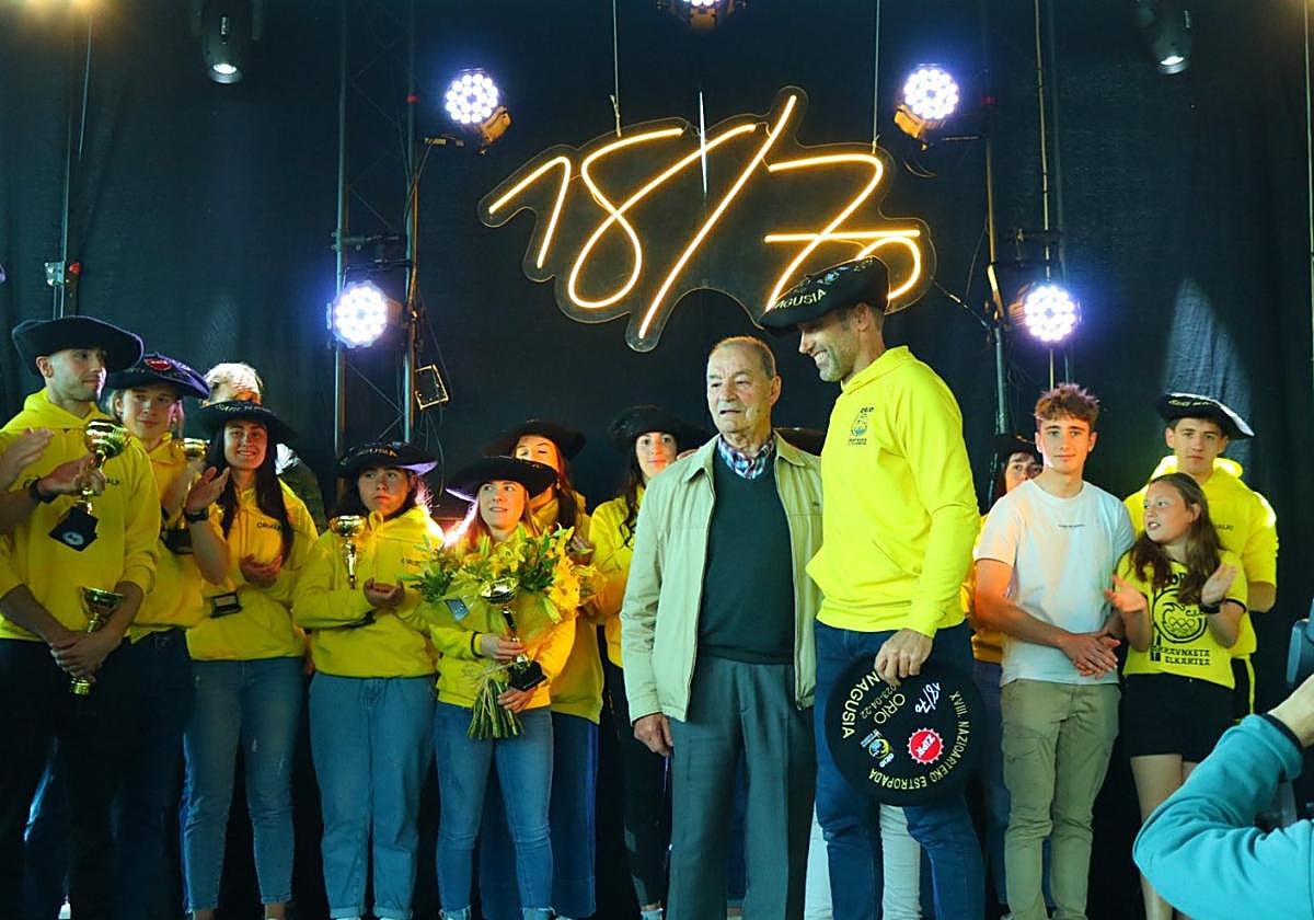 Jon Salsamendi arropa al homenajeado Patxi Sarasua con los remeros y remeras oriotarras detrásp