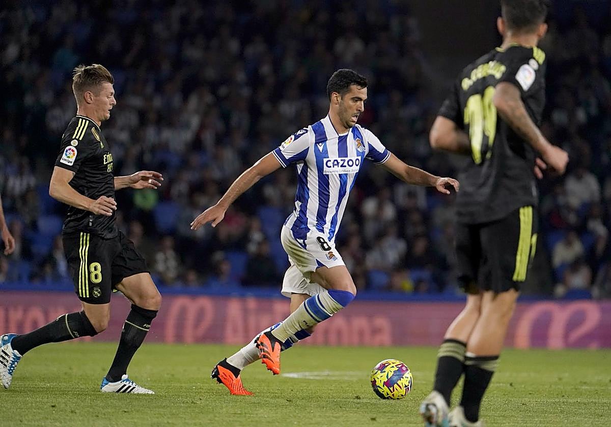 Merino conduce un balón perseguido por Kroos en el centro del campo.