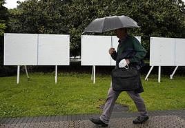 Un viandante transita junto unos paneles para anuncios electorales en San Sebastián en la jornada previa a la apertura de la campaña.