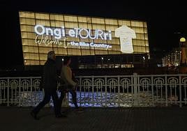 Dos ciudadanos observan la fachada iluminada del Kursaal que da la bienvenida al Tour a San Sebastián.