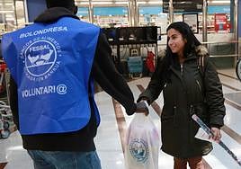 Una mujer se aproxima a los voluntarios del Banco de Alimentos para donar comida.