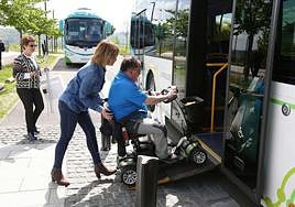 Un hombre en silla de ruedas accede a un autobús con ayuda de una acompañante.