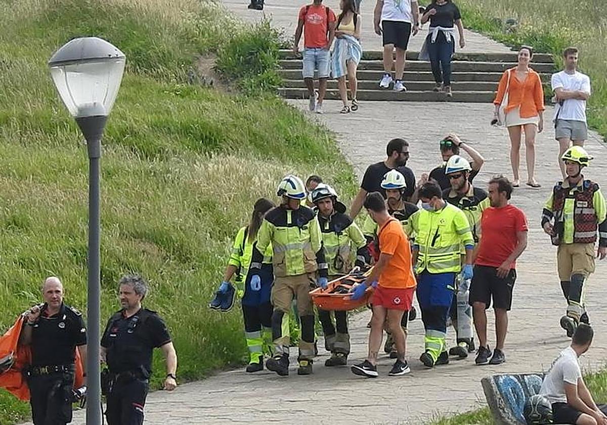 Bomberos y sanitarios trasladan al parapentista herido en la playa de Sopela.