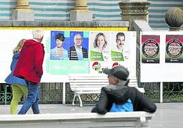 Una pareja pasa por delante de unos carteles electorales en Alderdi Eder, en San Sebastián.