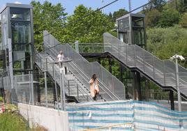 Dos usuarios en la zona de las escaleras y ascensores que están siendo instalados y renovados.