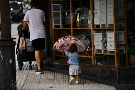 Una niña con su paraguas pasea junto a su padre por San Sebastián