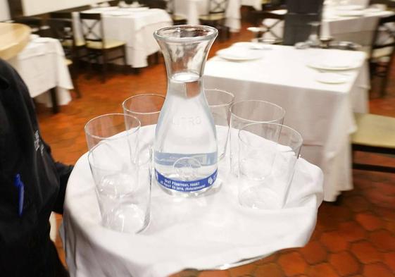 Un camarero sirve agua del grifo en un restaurante.