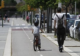 Un menor pasea con su padre en bicicleta.