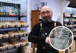 Javier Querejeta, en su tienda de la parte vieja de Donostia, con el cartel de aviso que ha colocado tras sufrir un intento de robo el pasado domingo.