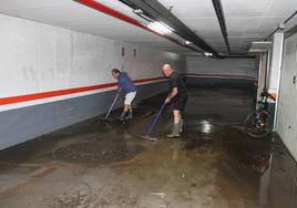 Dos vecinos limpian los garajes inundados ayer en Elgoibar