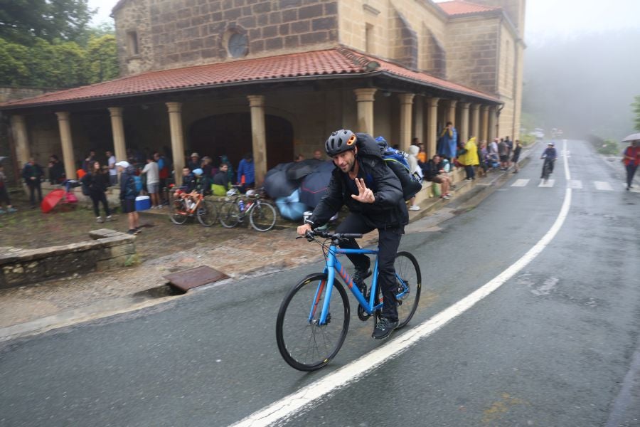 Un ciclista pasa por delante del Santuario de Guadalupe, en el monte Jaizkibel, donde muchos aficionados se resguardaban a primera hora de la lluvia.