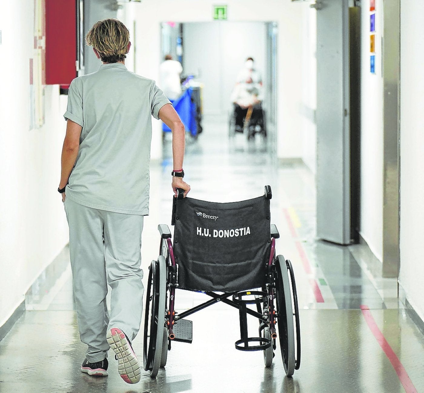 Una trabajadora del Hospital Universitario Donostia traslada una silla de ruedas.