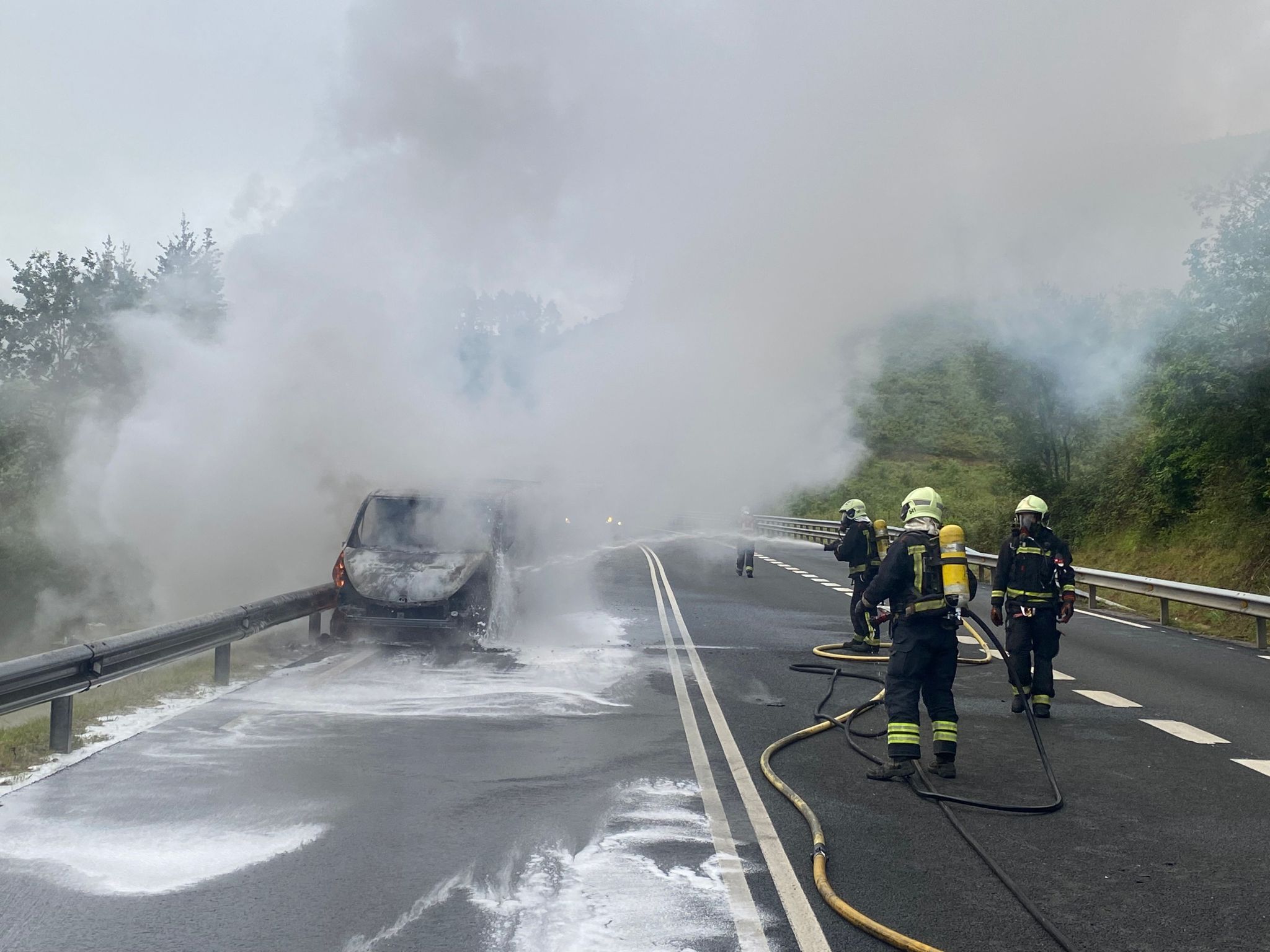 La furgoneta convertida en una bola de fuego en Azkarate mientras los bomberos tratan de apagar las llamas.