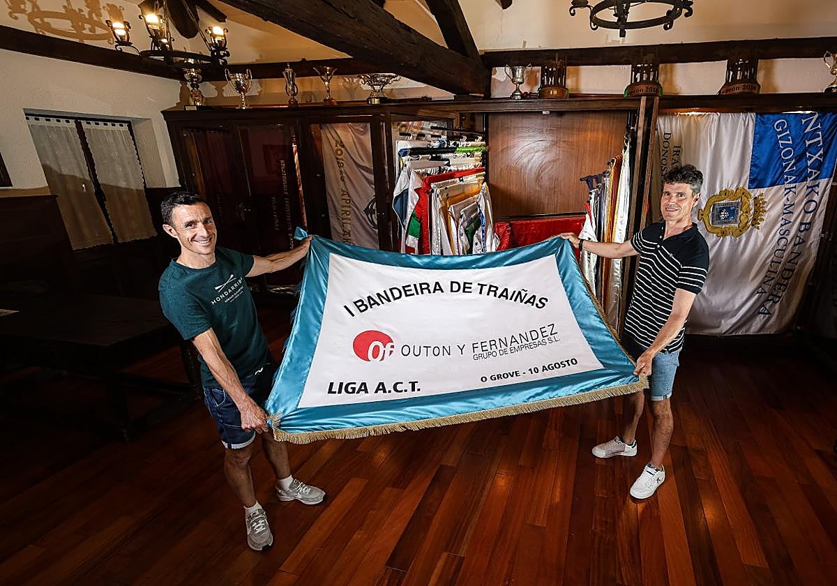 Joseba Amunarriz y Mikel Orbañanos despliegan la primera bandera que ganaron con Hondarribia en O Grove en la sala de trofeos del club.