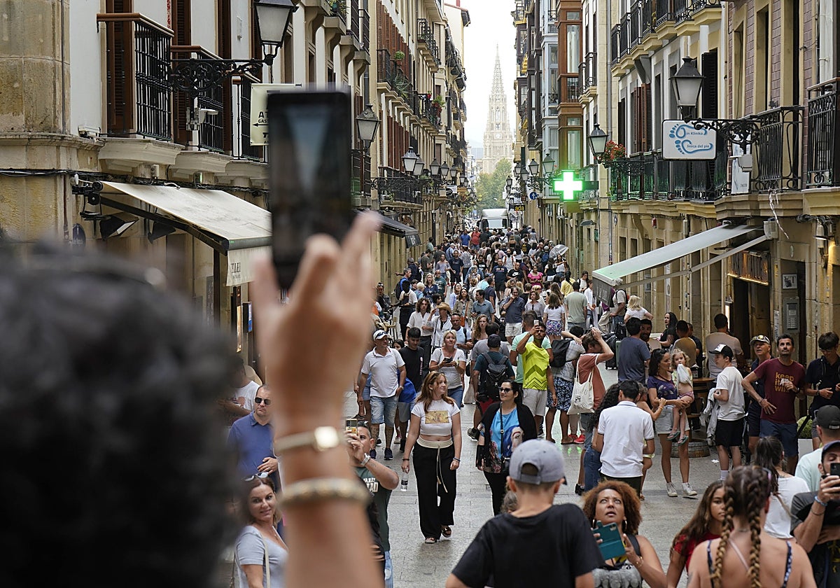Una turista saca una foto de la calle Mayor de Donostia llena de personas.