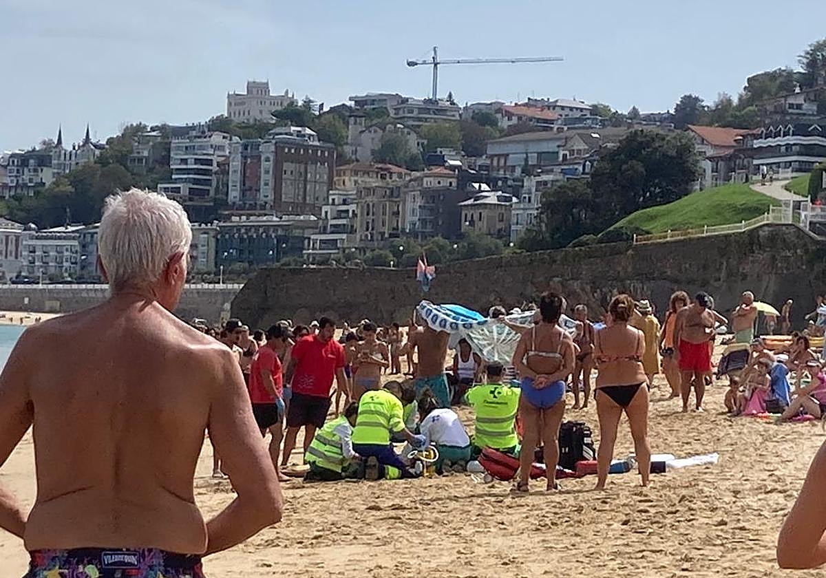 Socorristas y personal sanitario dan los primeros auxilios al joven rescatado en la playa de Ondarreta