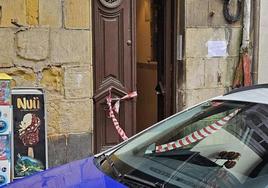 Un coche de la Ertzaintza frente al portal donde residía el fallecido en el que esta mañana se ha colocado un cartel en su memoria con la frase 'Mikel gogoan zaitugu'.