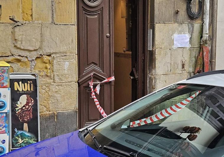 Un coche de la Ertzaintza frente al portal donde residía el fallecido en el que esta mañana se ha colocado un cartel en su memoria con la frase 'Mikel gogoan zaitugu'