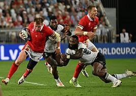 Un jugador galés evita el placaje de un fidjiano.