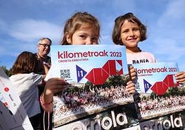 Orereta Ikastolako bi ikasle Kilometroak jaiaren kartelarekin.